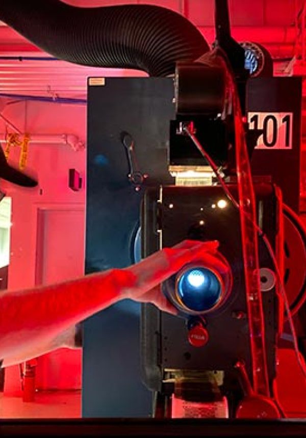 Technician adjusting a film projector in a room lit with red lighting