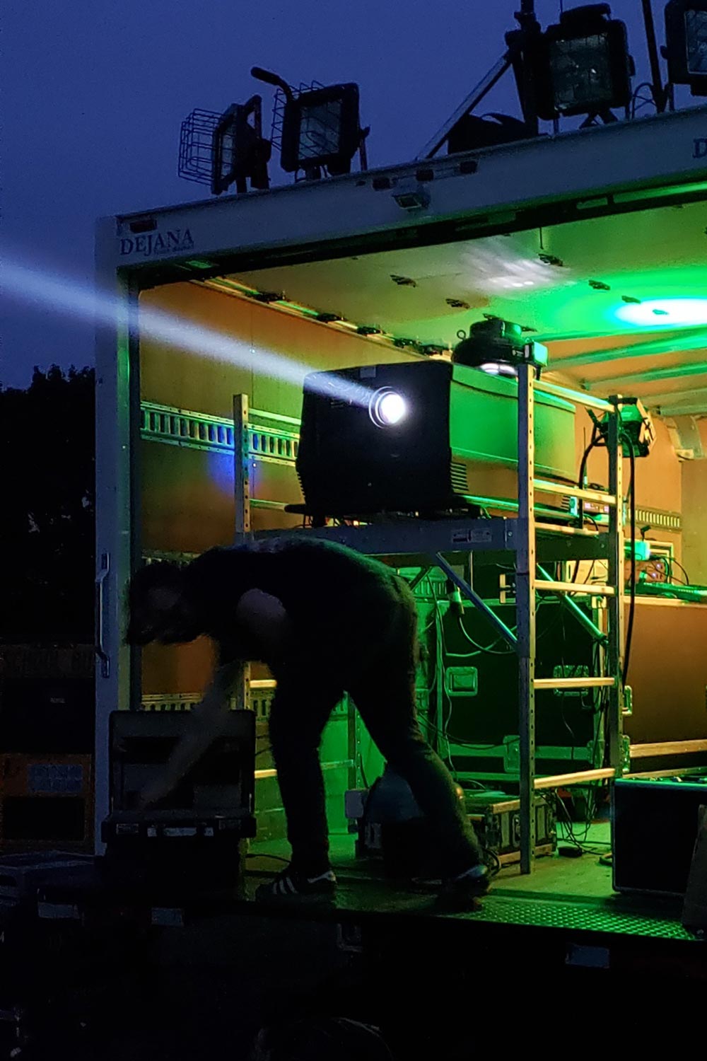 Technician setting up outdoor projector in truck with bright beam of light