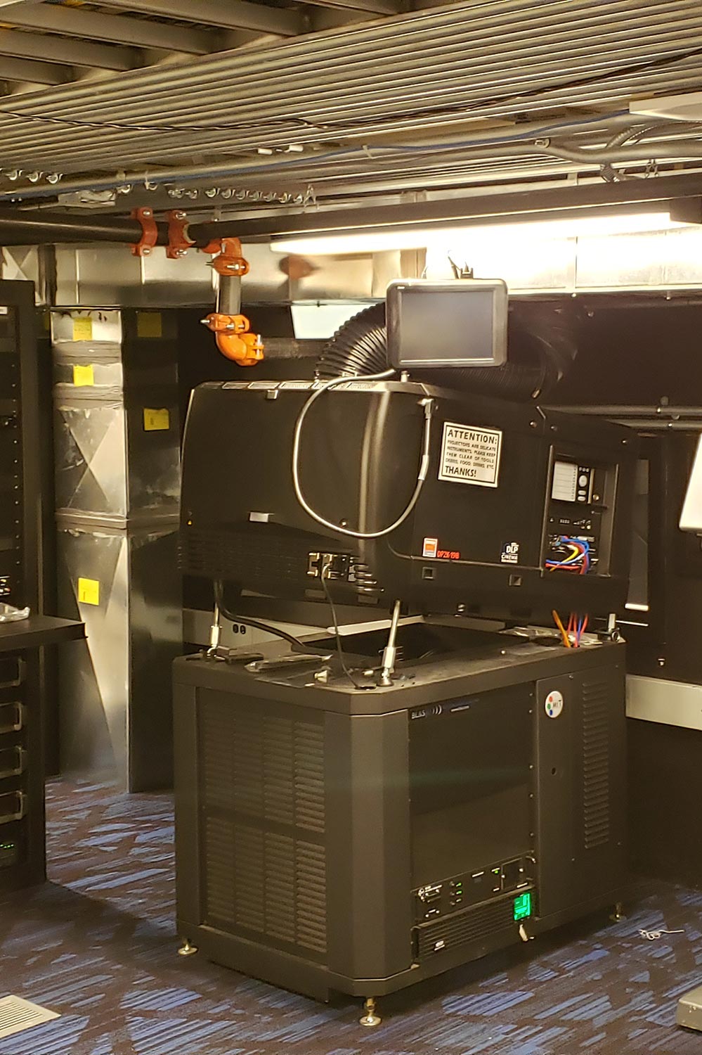 Digital cinema projector setup in a theater projection booth with cables and control equipment
