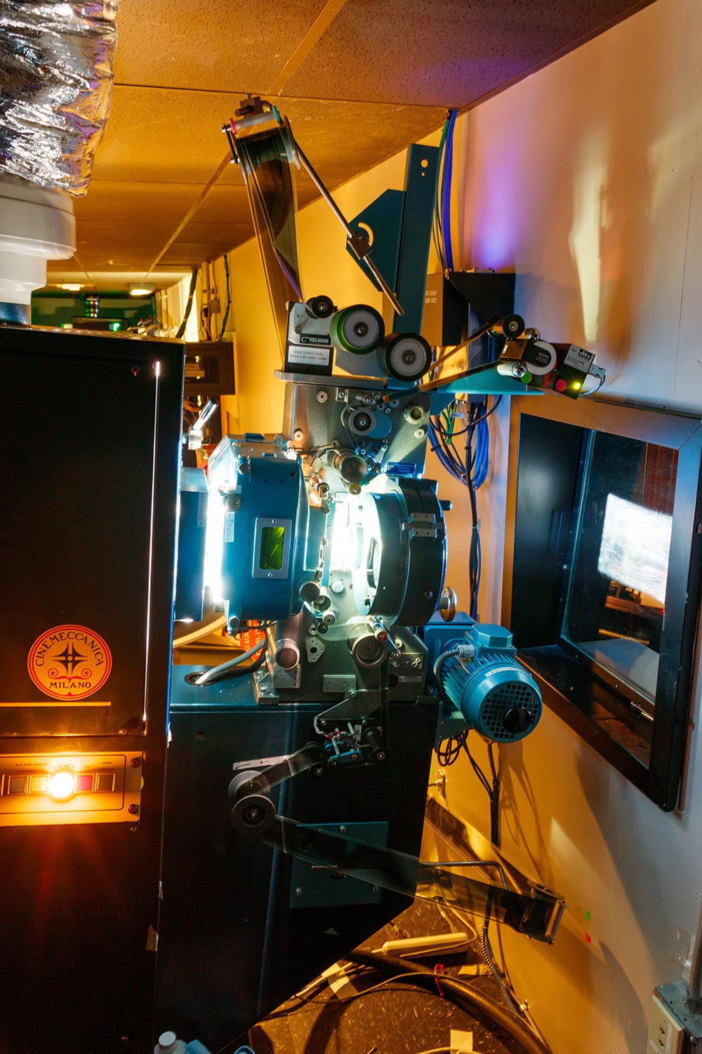 Film projector in operation projecting light through a window in a theater booth