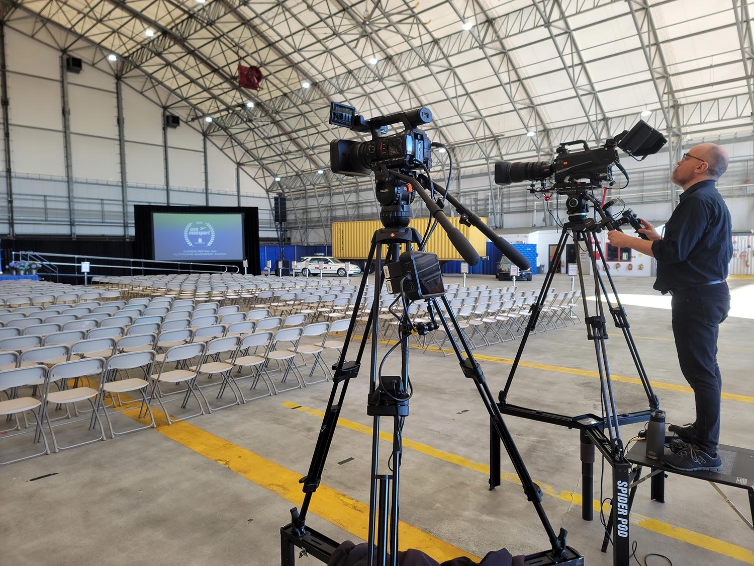 Cameraman setting up professional video cameras in an airplane hangar event space