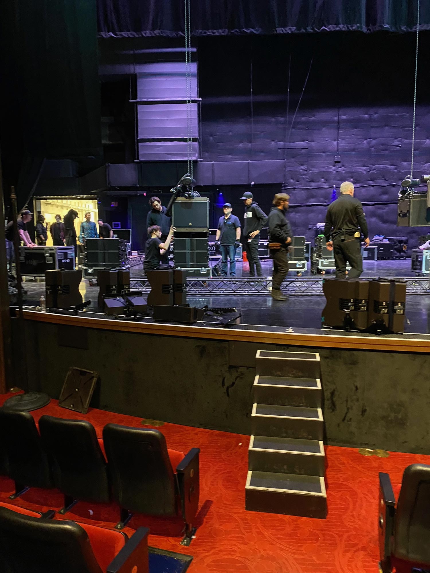 Crew setting up stage equipment with lighting trusses in a theater