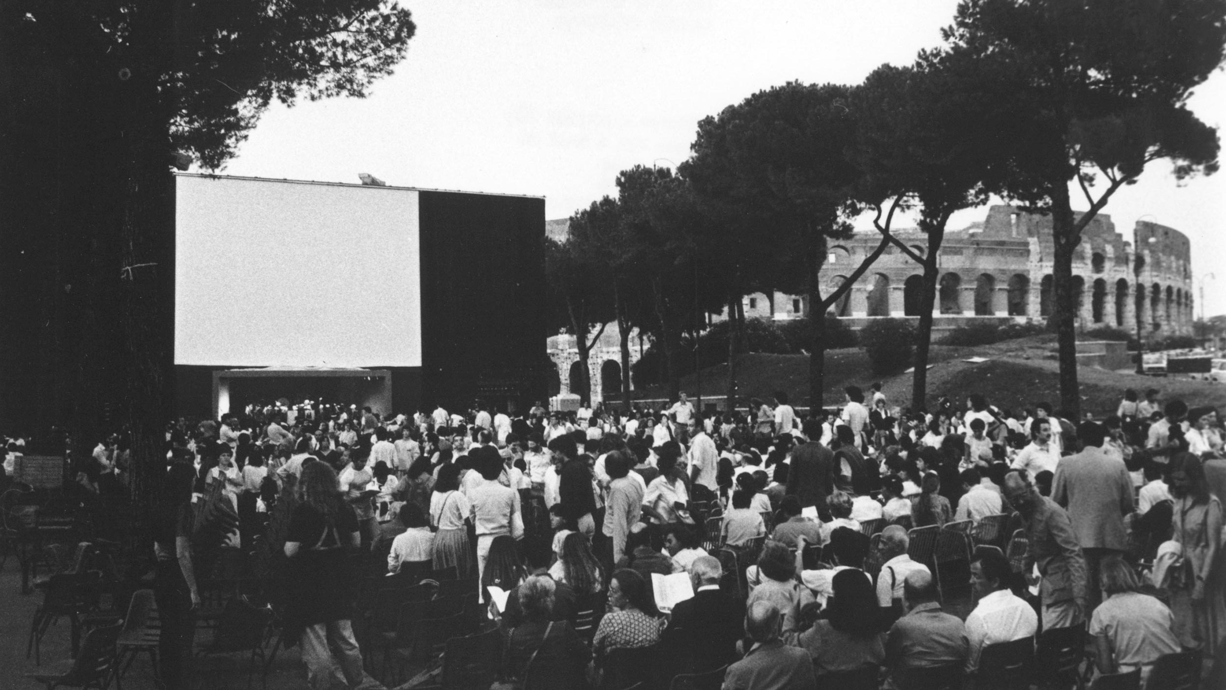 Outdoor film screening setup near the Colosseum with a large crowd gathering