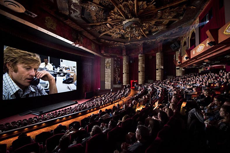 Lavish cinema with decorative ceiling showing a movie to full audience