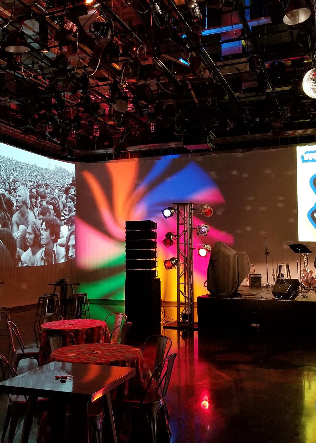 Colorful lighting setup in an event space with tables and a stage