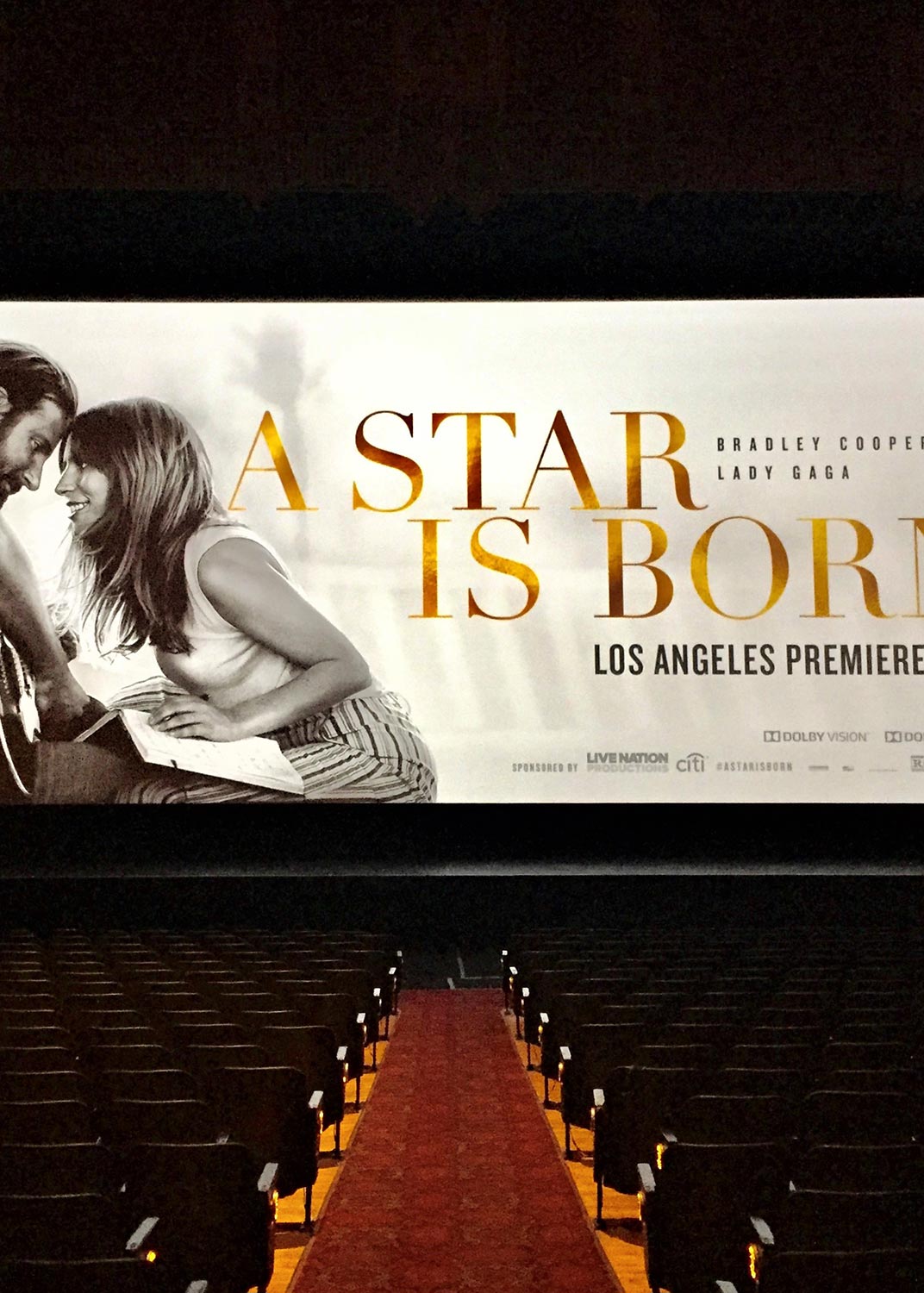 Large movie screen showing A Star Is Born poster in an empty theater