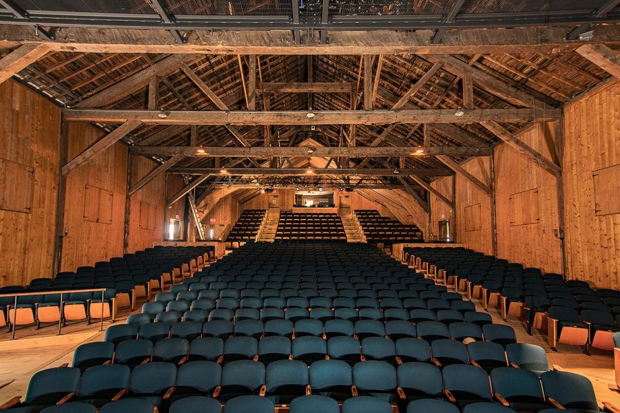 Rustic wood and stone building with a modern wooden extension in a wooded area