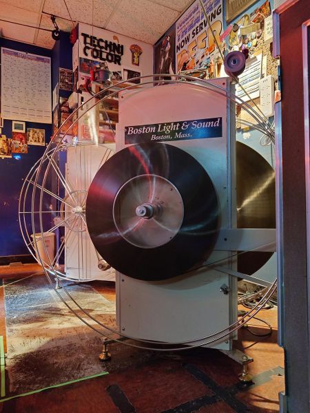 Large silver film platter system holding a movie reel in a messy room