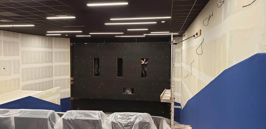 Theater under construction with exposed walls and a person working on wall