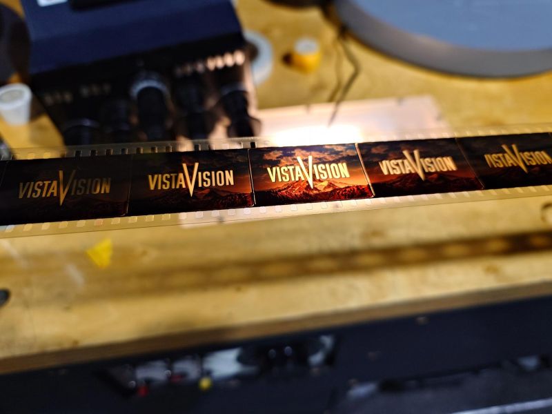 Backlit horizontal film strip showing landscape and text frames on a wooden table