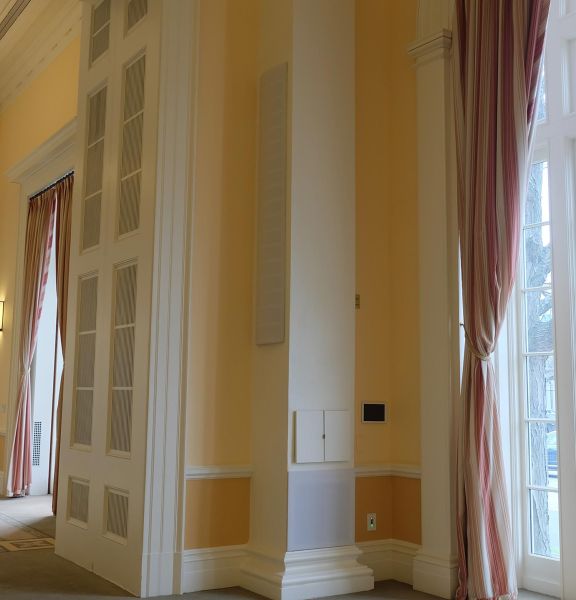 Elegant ballroom corner with tall windows, curtains, and integrated speakers
