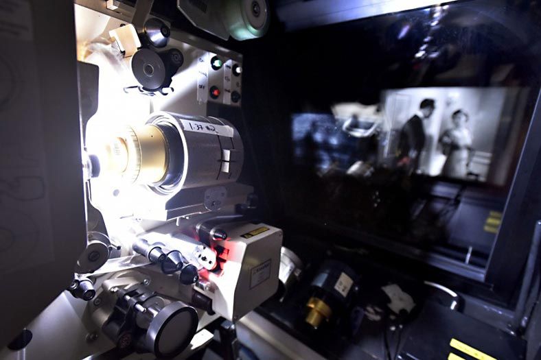 Film projector in action with black-and-white movie visible through window
