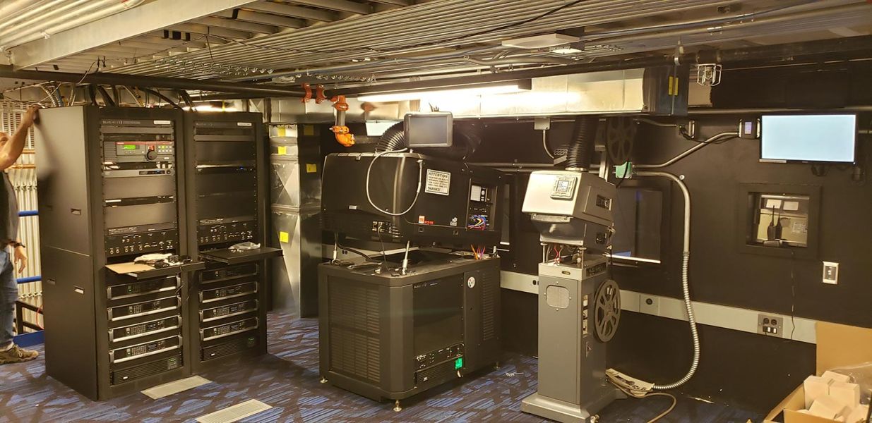 Group of people posing in front of a large blank movie screen in a theater