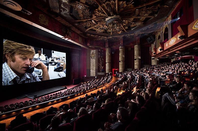 Lavish cinema with decorative ceiling showing a movie to full audience