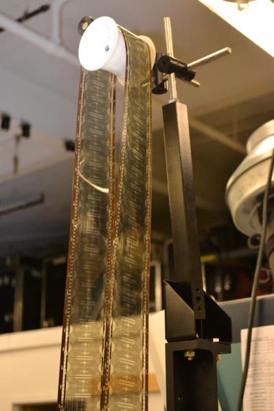 Technician working on a film projector in a storage room