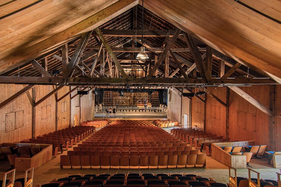 Interior view of a barn-style theater with exposed beams and orange theater seats