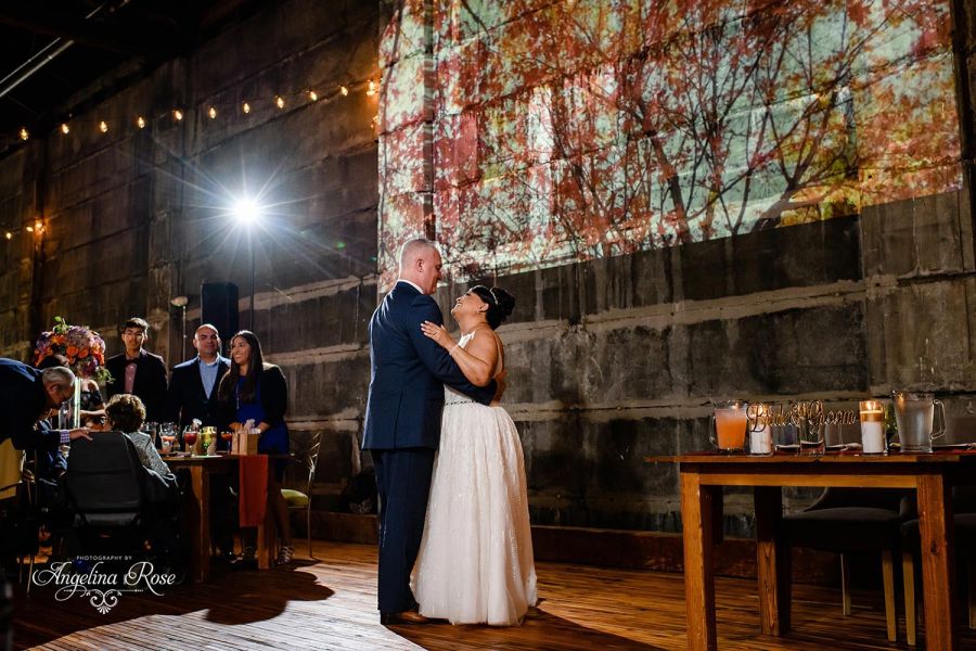 Bride and groom dancing with autumn imagery projected on wall
