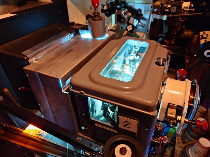 High-angle view of a grey metal film projector with a glowing glass window