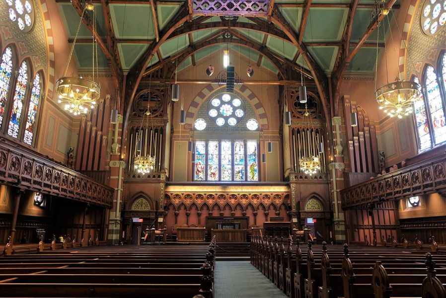 Church sanctuary with stained glass windows and hanging cylindrical speakers