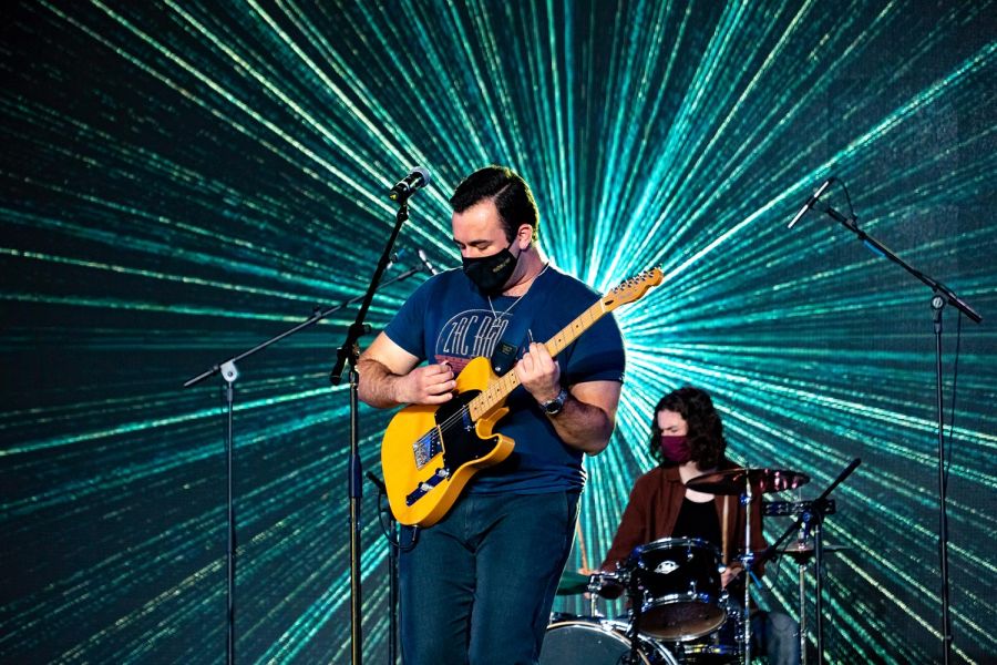 Guitarist and drummer performing in front of starburst LED screen