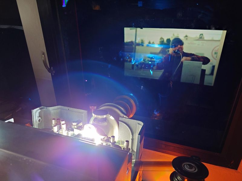 Vintage film projector glowing brightly inside a dark projection booth