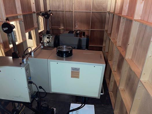 Inside a wooden projection booth with vintage film equipment setup