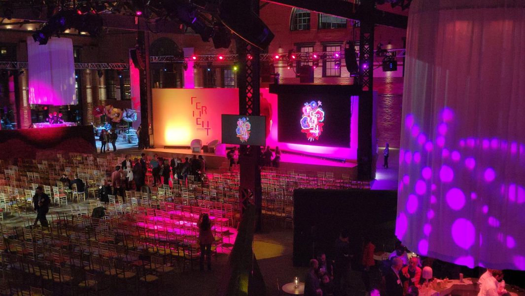 Colorfully lit indoor venue with rows of chairs and a vibrant stage
