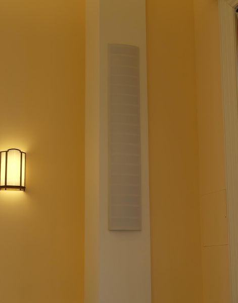Discreet wall-mounted speaker on a cream and yellow accent wall