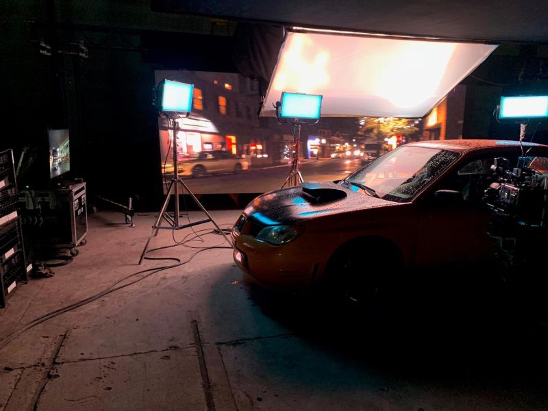 Film set with car in front of backdrop and lighting for night scene